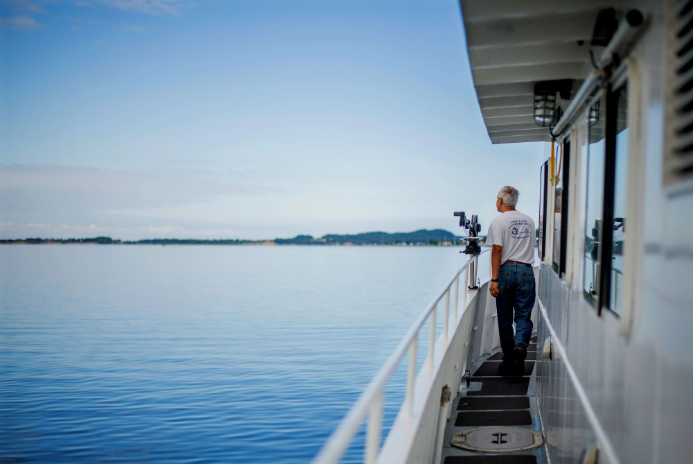a man standing on a boat looking out at the water