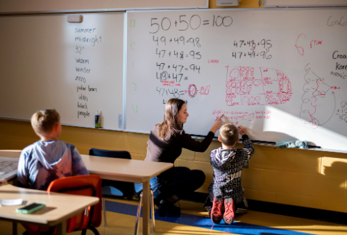 a teacher writing with a student on a white board