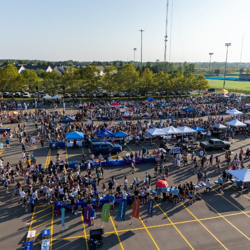 Overhead shot of a parking lot filled with students and tables at Campus Life Night