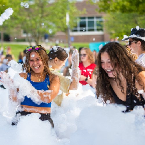 Two students laughing and playing in the foam at Laker Kickoff