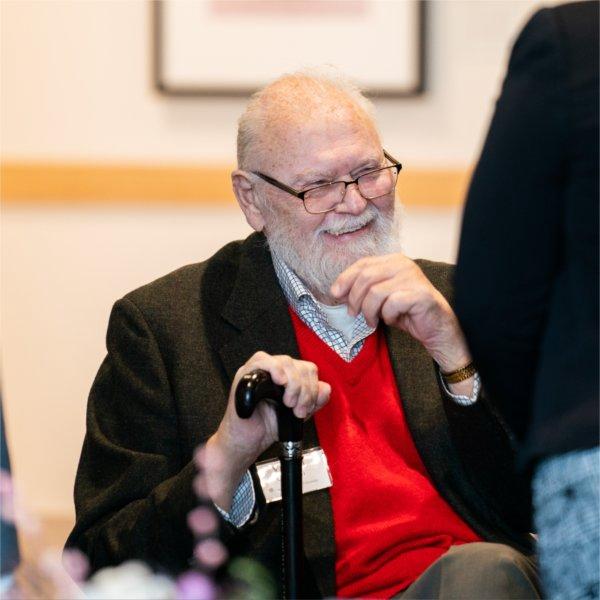 Vernon Ohlman seated with hand on cane laughing