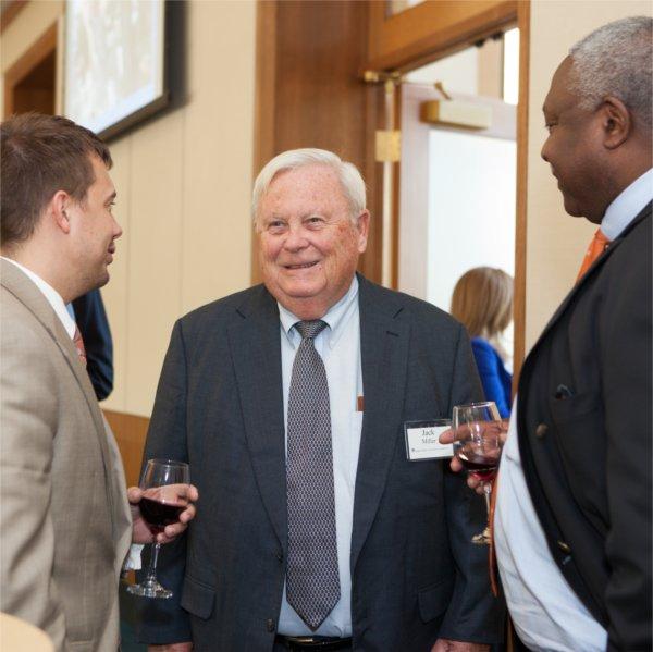 Jack Miller in center between two men who are holding glasses of wine